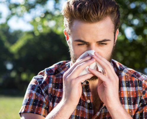 Man blowing his nose, fighting off Spring Allergies